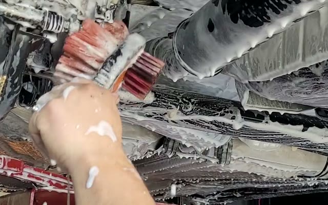 Escovação com espuma na parte inferior do veículo durante a limpeza de chassi.
